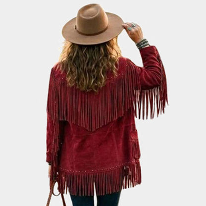 A woman shown from the back wearing a rust-red fringe jacket, a tan wide-brim hat, and blue jeans against a light gray background.