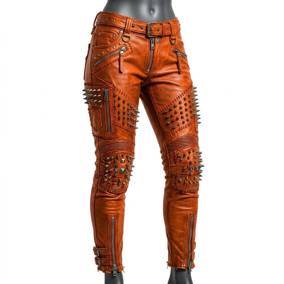  Front view of women orange studded leather pant with spike and zipper detail